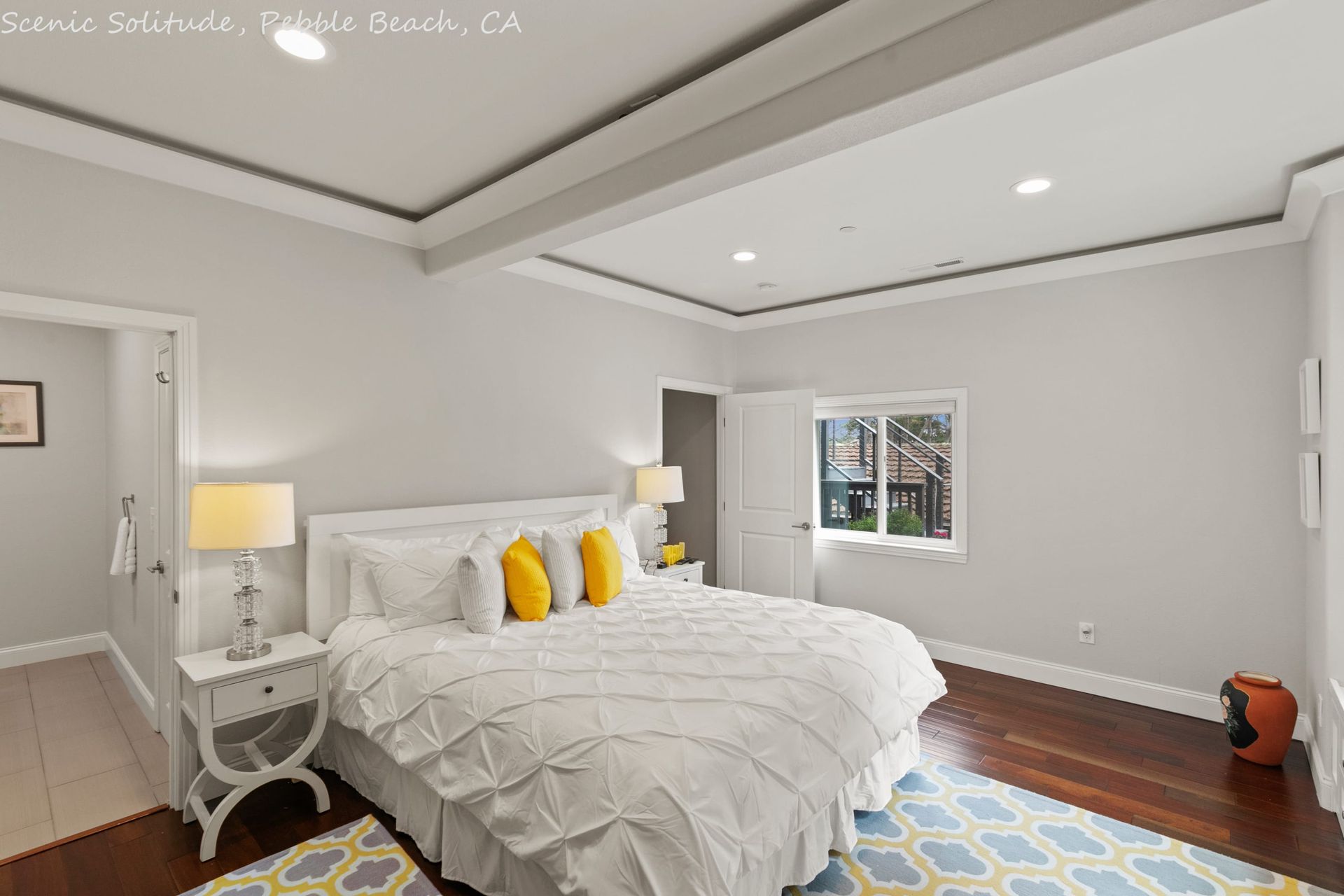 A bedroom with a large bed , two nightstands , a rug and a window.