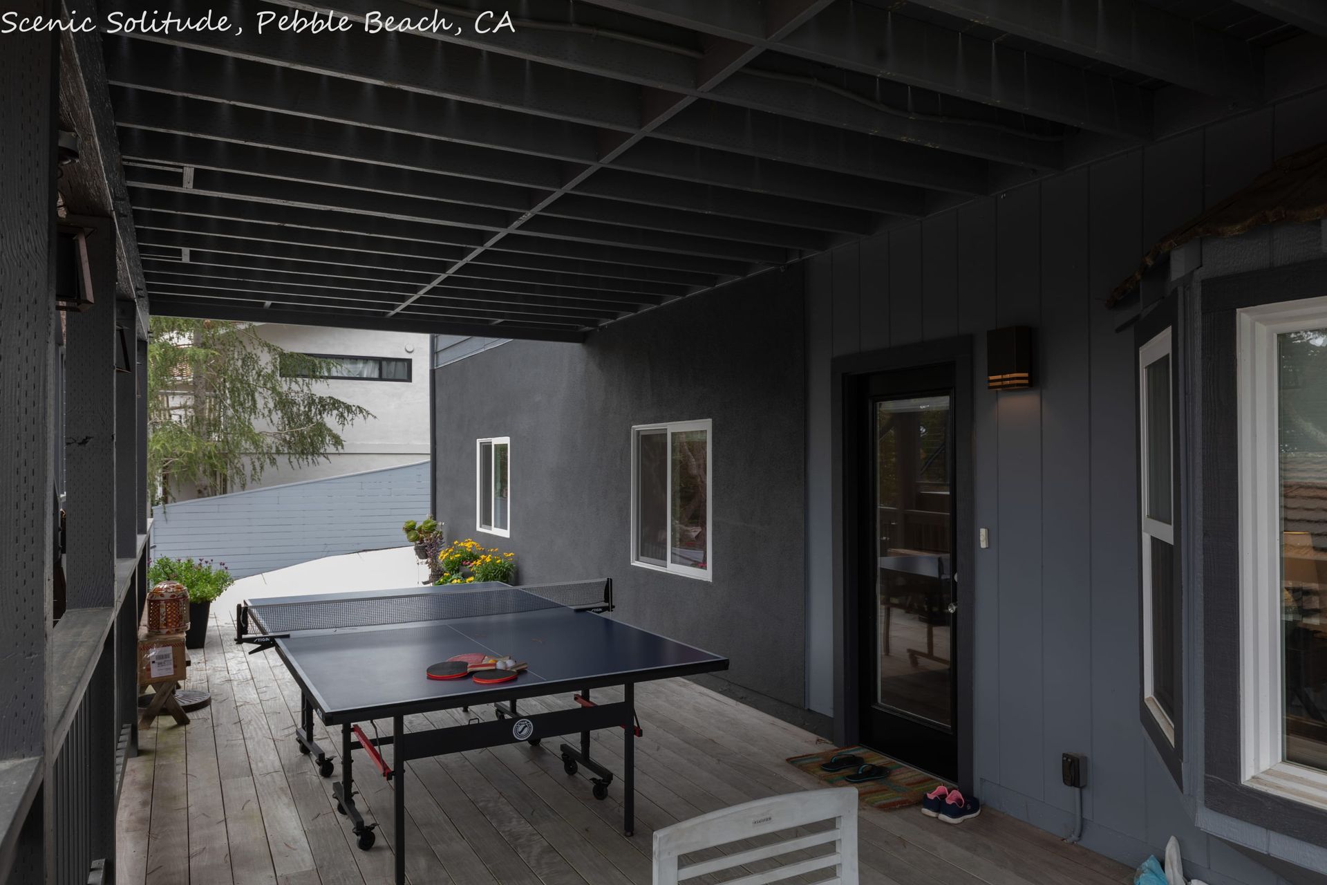 A ping pong table is on the deck of a house.