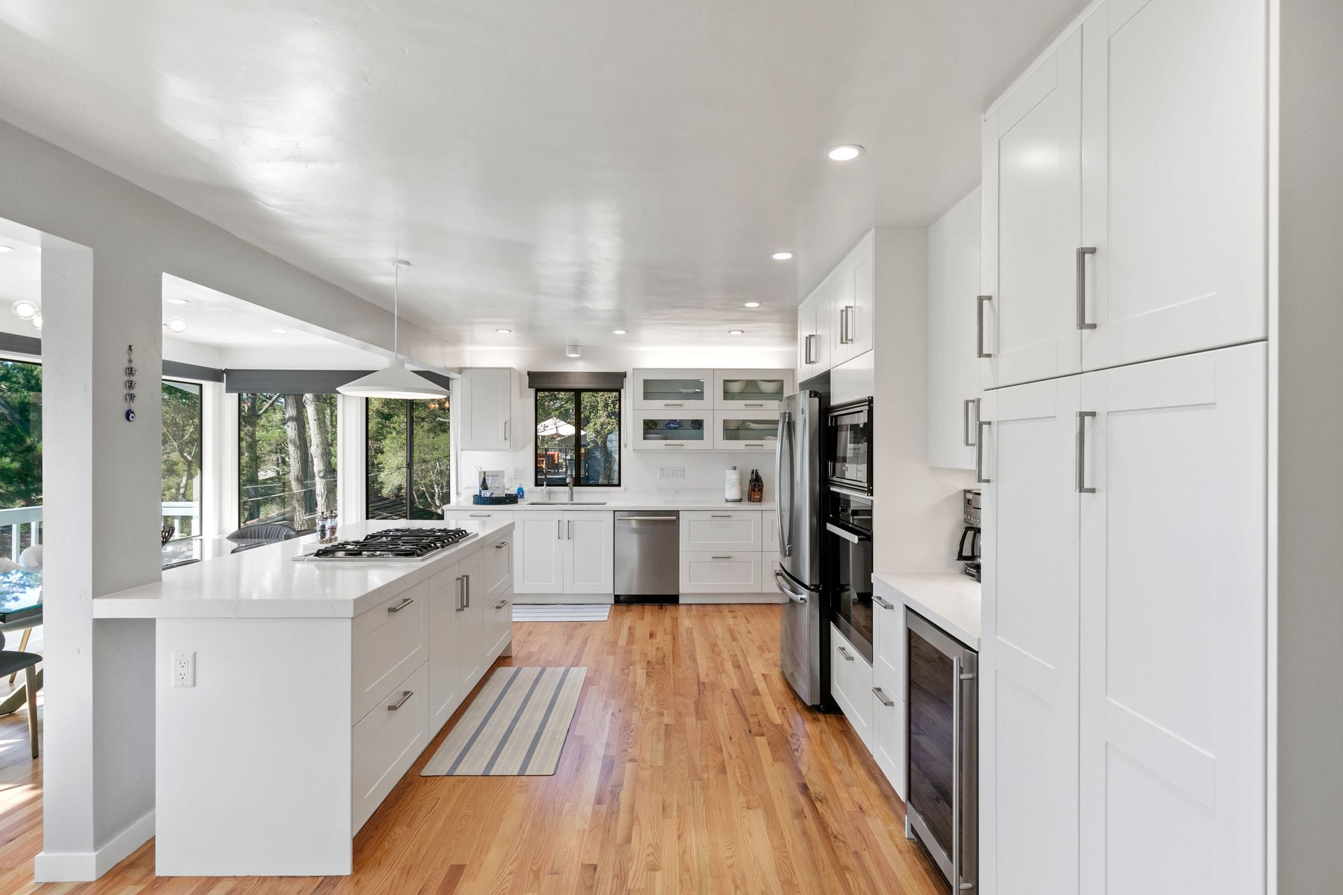 A kitchen with white cabinets , hardwood floors , and stainless steel appliances.