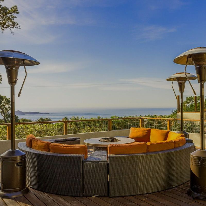 A patio with a couch and heaters with a view of the ocean