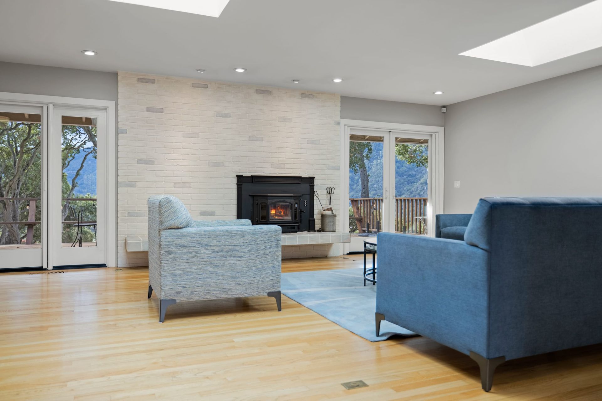 A living room with a couch , chair , fireplace and sliding glass doors.