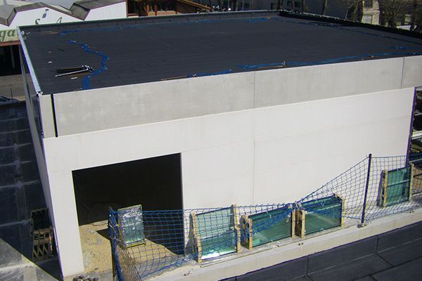 Un edificio blanco con un techo negro y una valla alrededor.