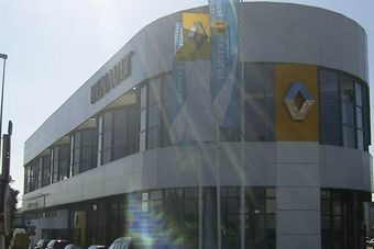 Un concesionario de coches Renault con muchos escaparates y coches aparcados delante.