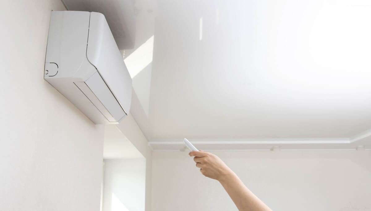 Una persona está usando un control remoto para controlar un aire acondicionado.