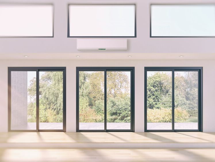 Una habitación vacía con muchas ventanas y un ventilador de techo.