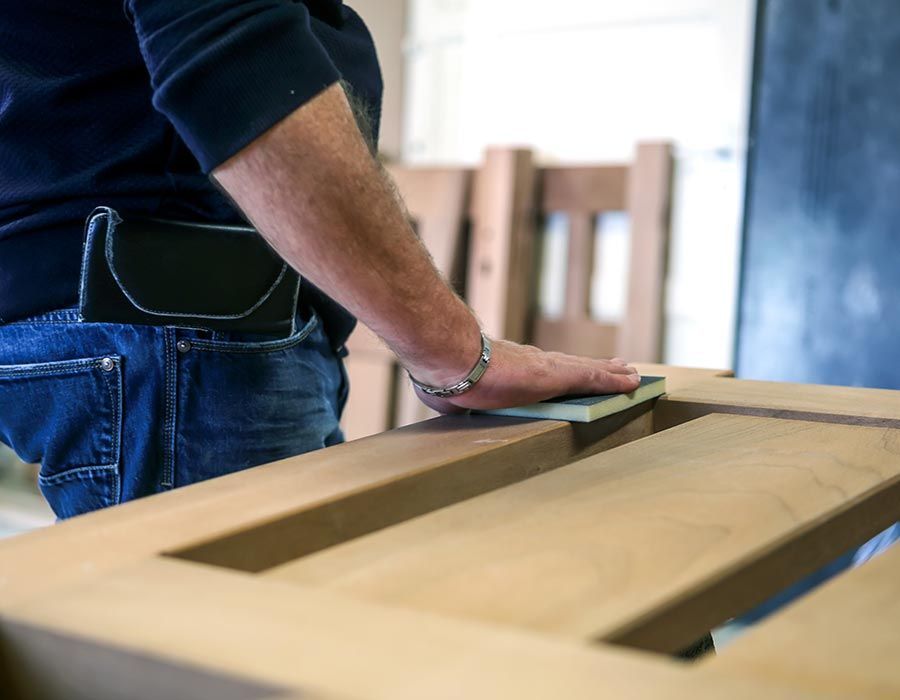 vue de près de la main d'un ouvrier qui ponce une pièce de bois
