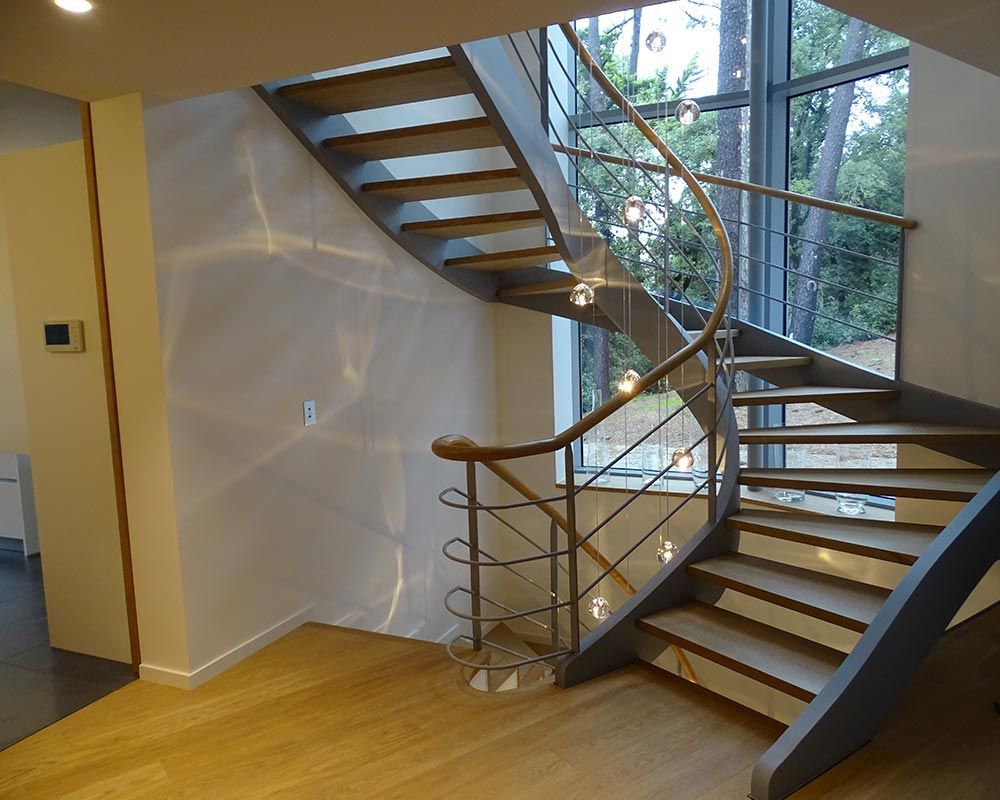 escalier en colimaçon ajouré en bois clair et montants noirs
