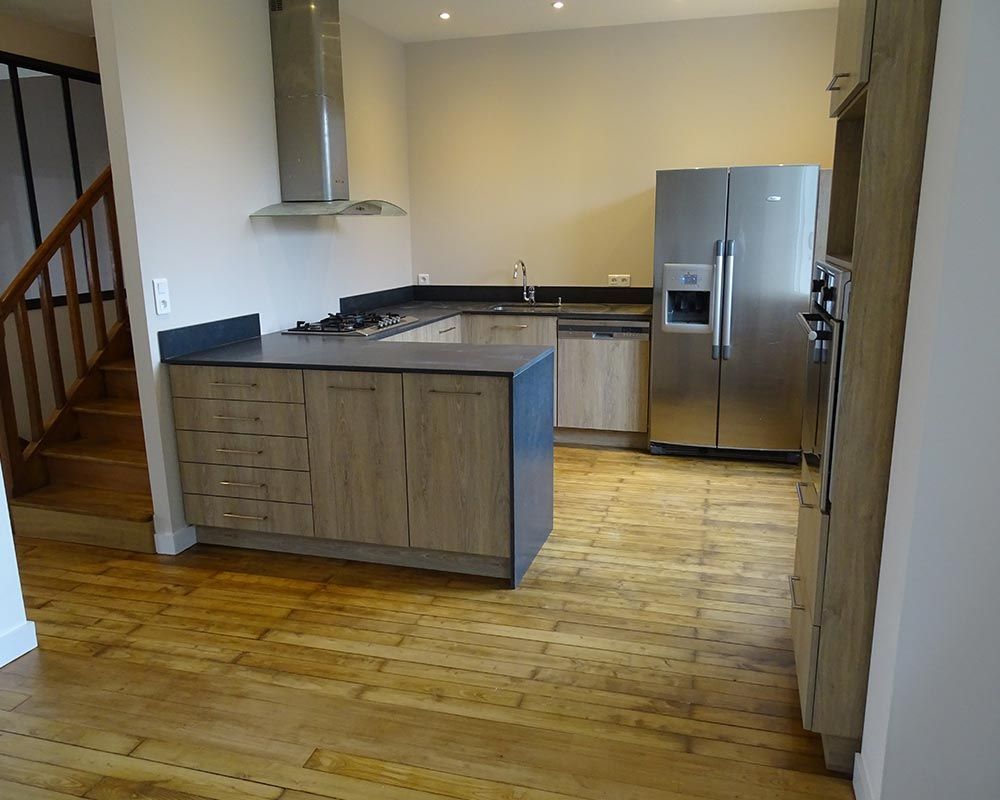 cuisine aménagée en bois, plan de travail gris, et l'électroménager chromé