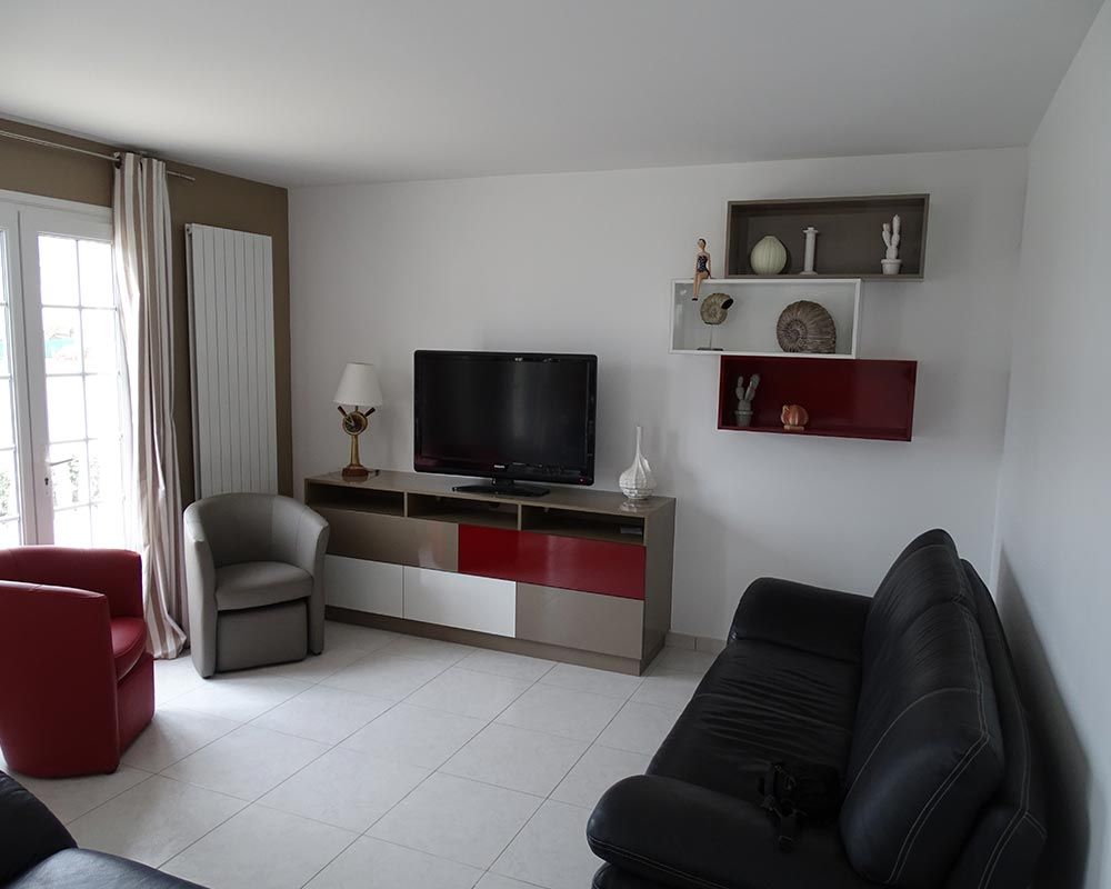 meuble accueillant la TV dans un salon aux teintes bordeaux, blanc et noir