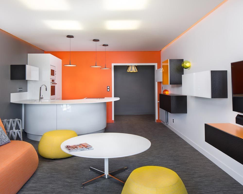 espace cuisine au design arrondi et brillant, adossé à un mur orange