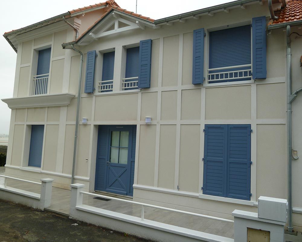 façade d'une maison agrémentée de bois blanc et de volets bleus