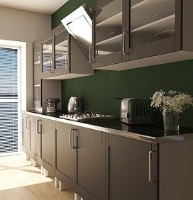 Cocina moderna con gabinetes oscuros, salpicadero verde, electrodomésticos sobre encimera y luz natural que entra por una puerta de cristal.