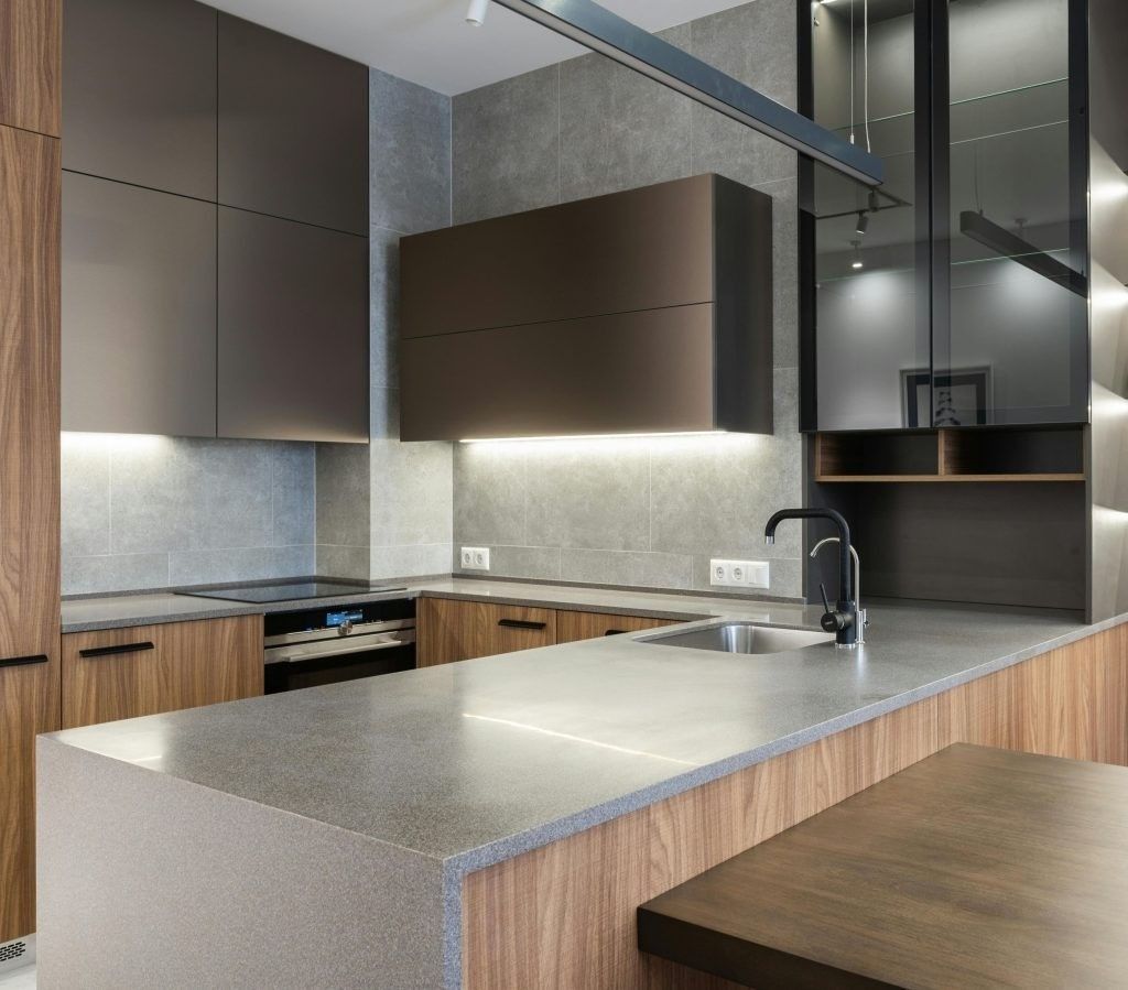 Cocina moderna minimalista con gabinetes de madera, isla de mármol y fregadero de acero inoxidable bajo iluminación tenue.