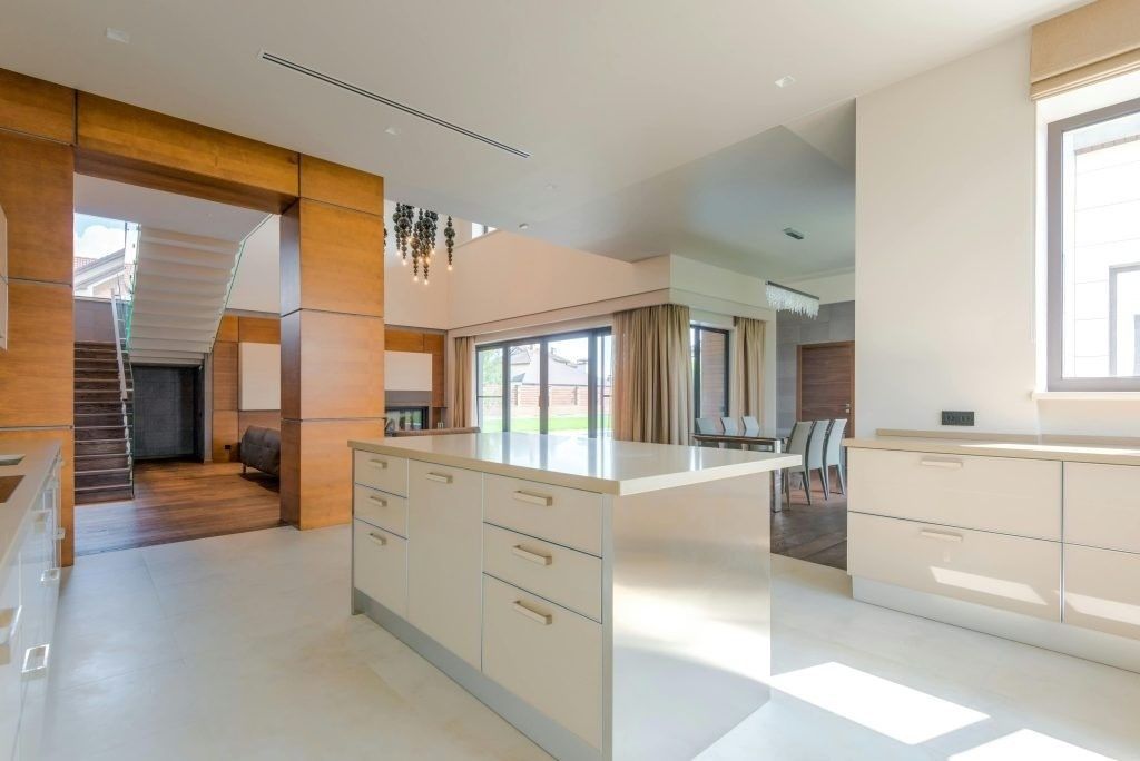 Cocina moderna y luminosa con isla blanca, detalles en madera y grandes ventanales con vistas a un patio.