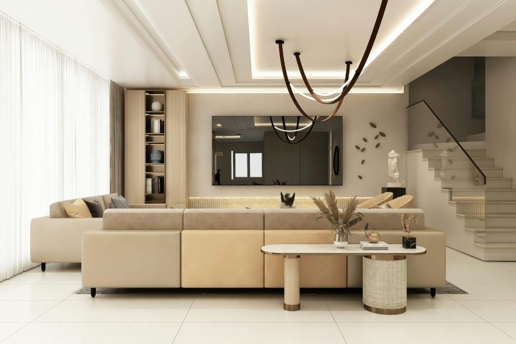 Sala de estar moderna de color beige con sofá modular, mesa de centro, lámpara de araña y escalera al fondo.