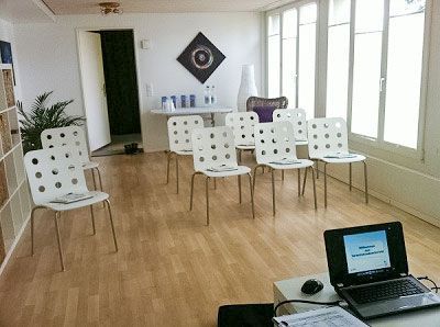Ein Konferenzraum mit weißen Stühlen, einem Tisch mit Wasserflaschen und einem Laptop auf einem Tisch.