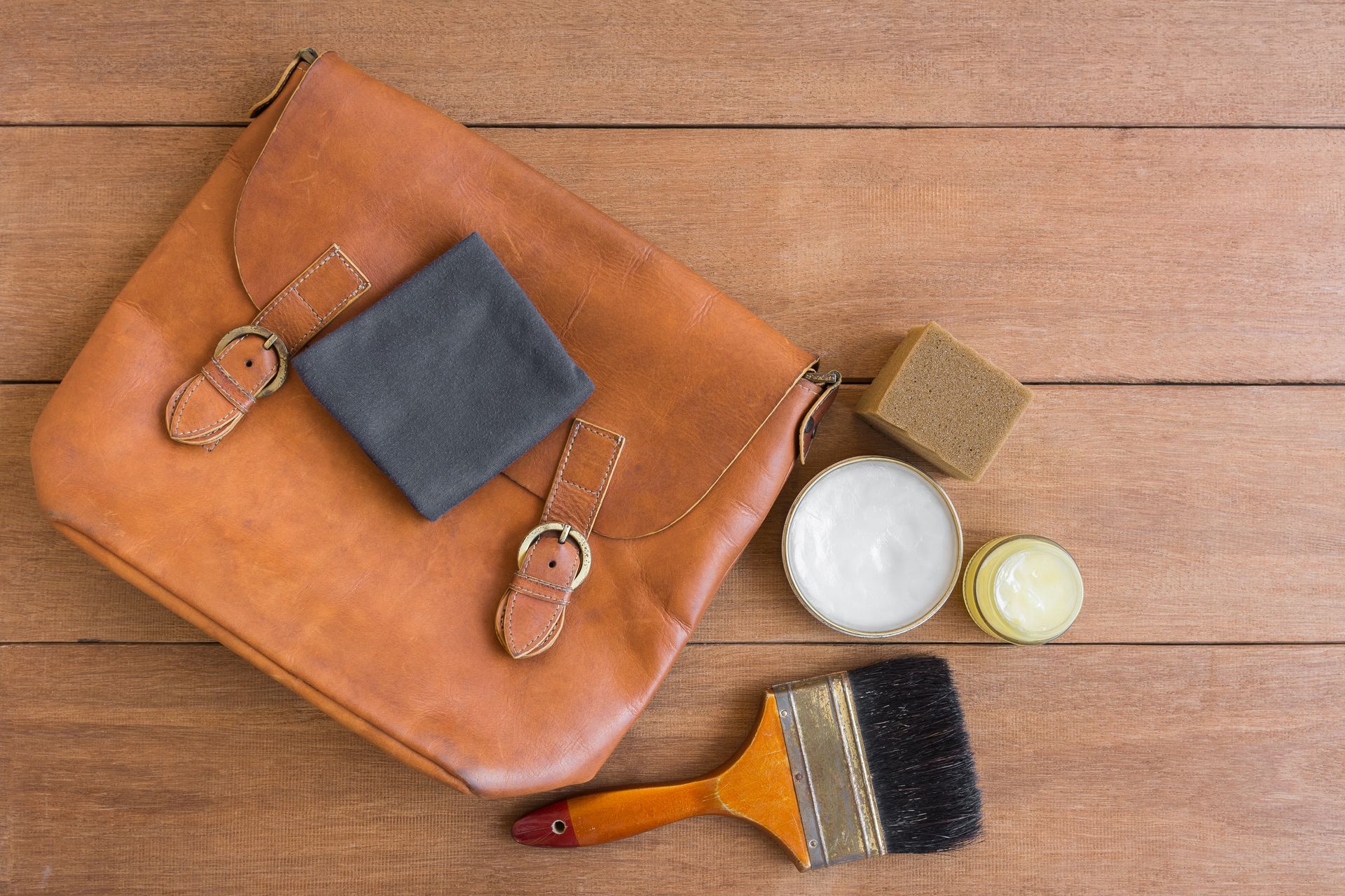 Un sac à main avec un pinceau, un chiffon et du cirage.