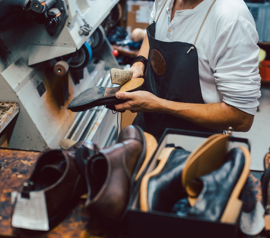 Un cordonnier façonne une chaussure en cuir noir dans son atelier.