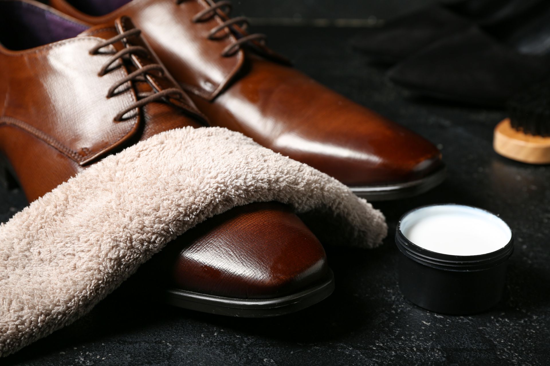 Derbies homme en cuir marron avec un chiffon et une boîte de cirage.