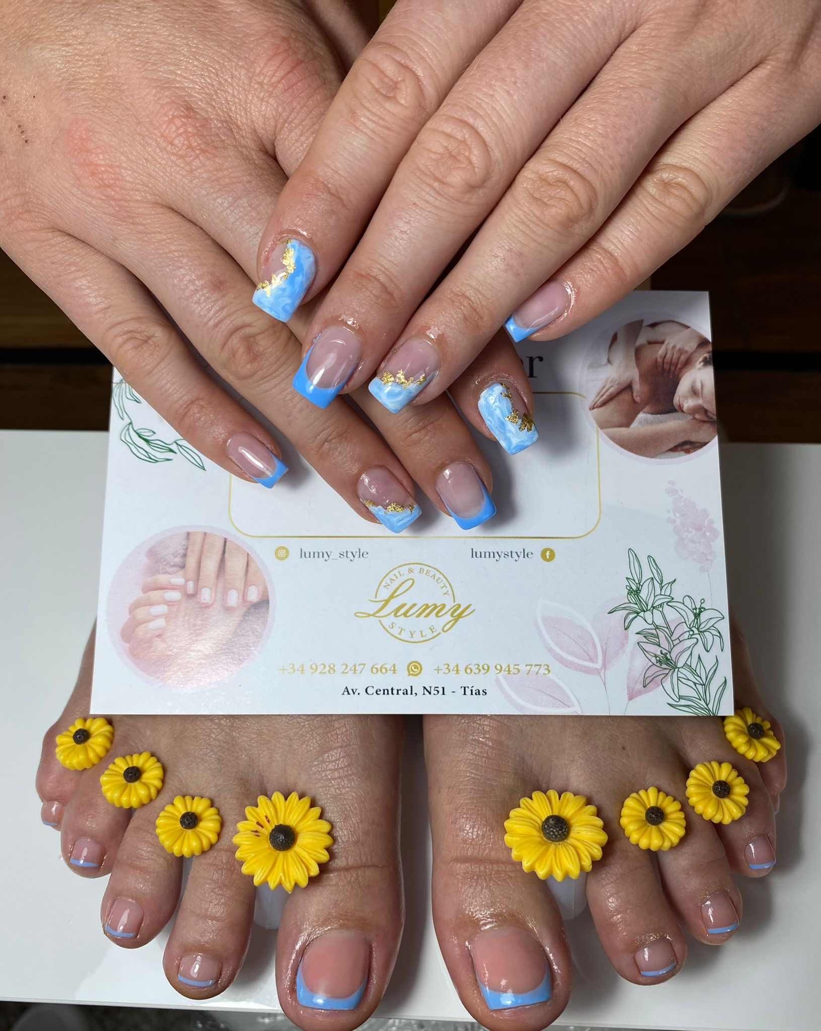 Un primer plano de las uñas de una mujer con girasoles.