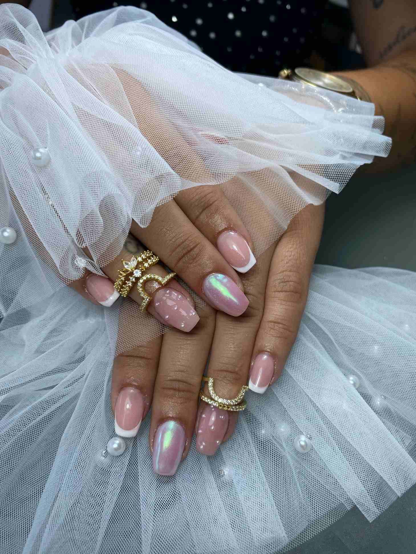 Un primer plano de las manos de una mujer con uñas rosas y anillos.