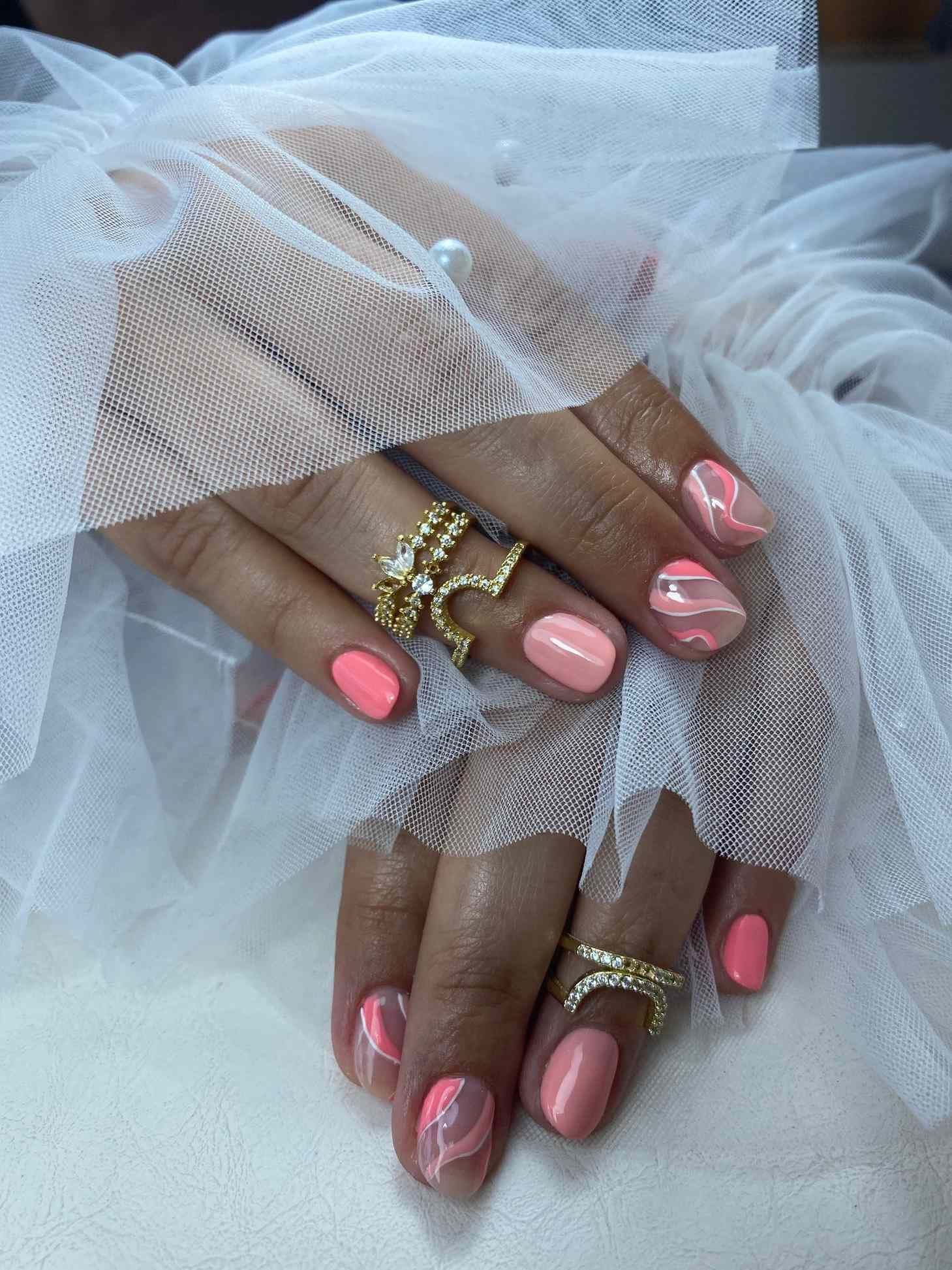 Un primer plano de las manos de una mujer con uñas rosas y anillos.