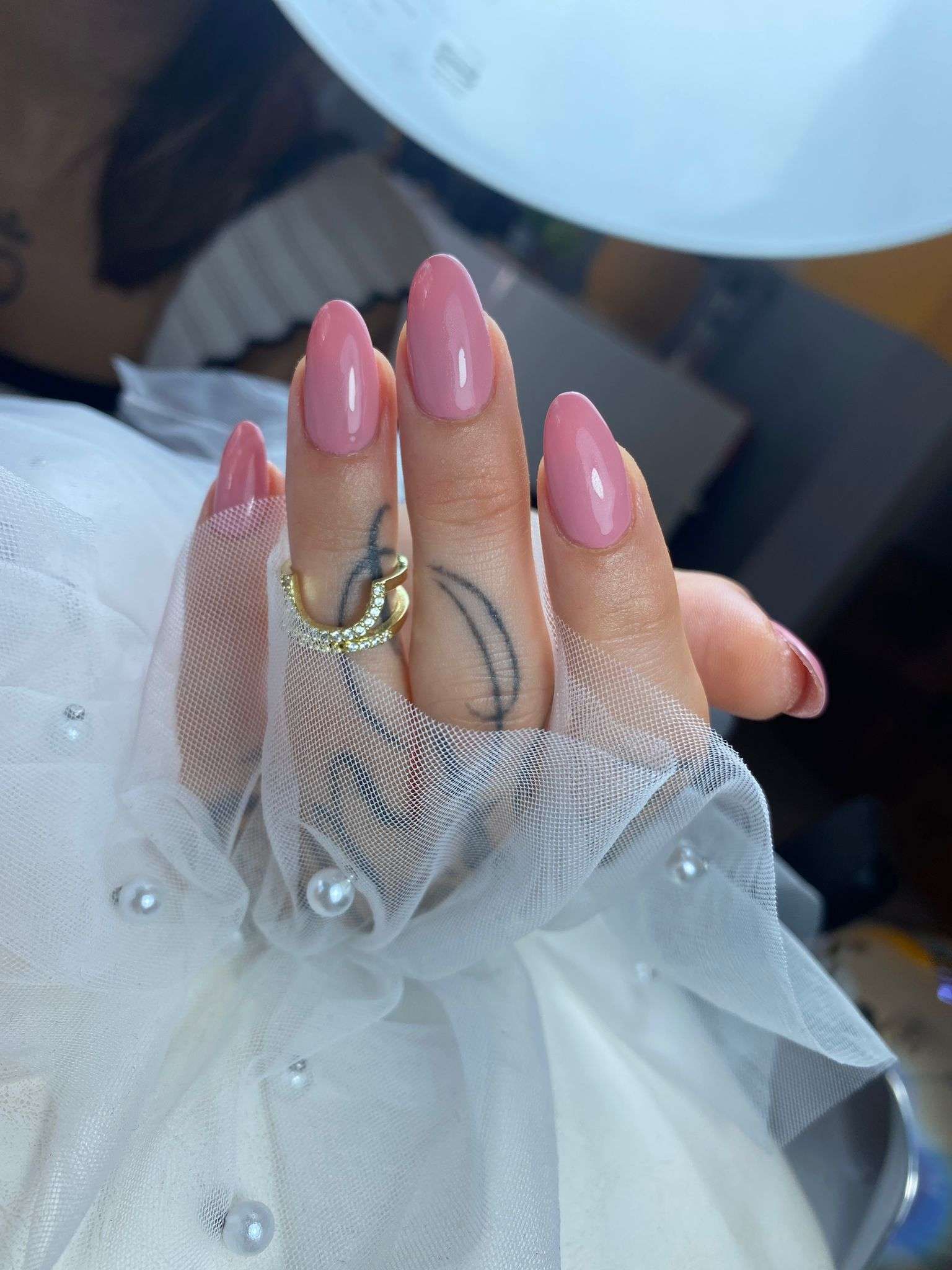 Una mano de mujer con uñas rosas y un anillo en el dedo.