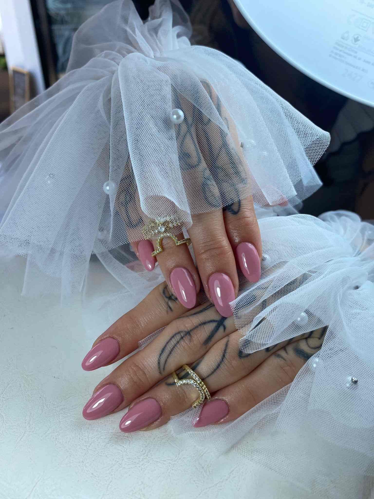 Un primer plano de las manos de una mujer con uñas rosas y anillos.