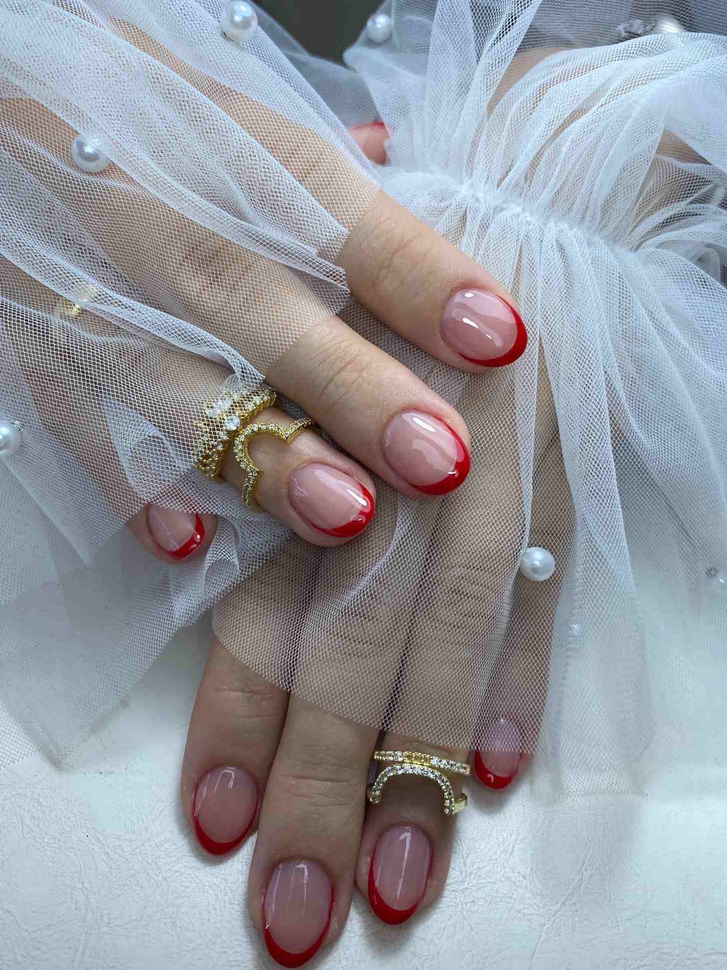 Un primer plano de las manos de una mujer con uñas rojas y anillos.