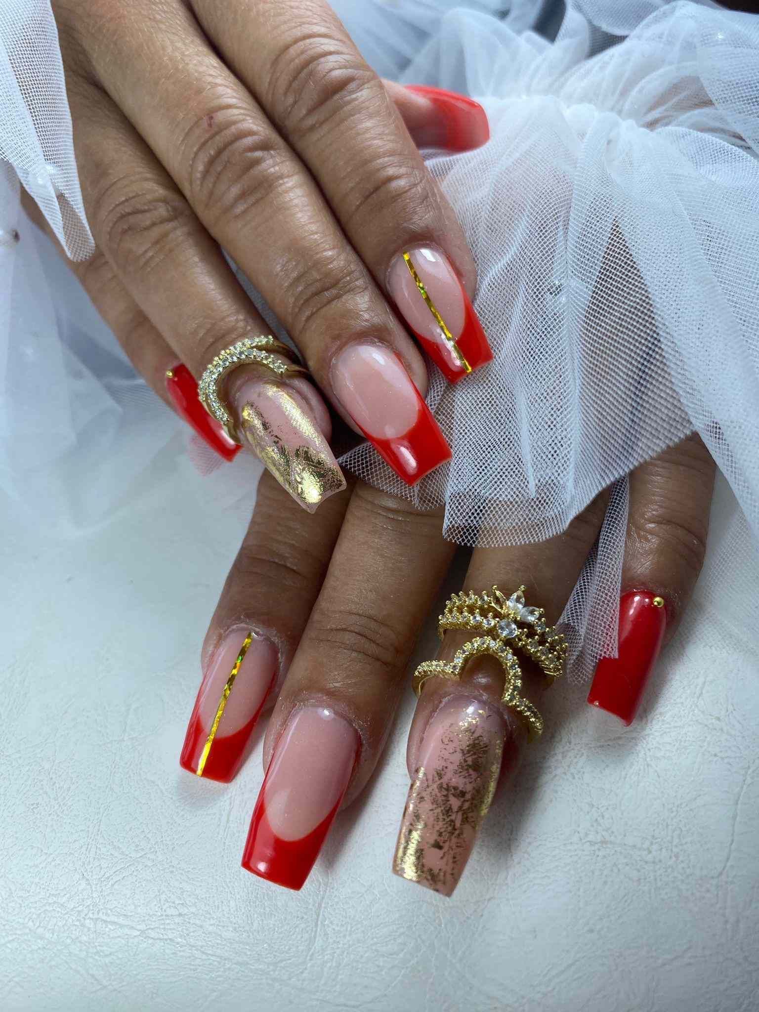 Un primer plano de las manos de una mujer con uñas rojas y doradas.