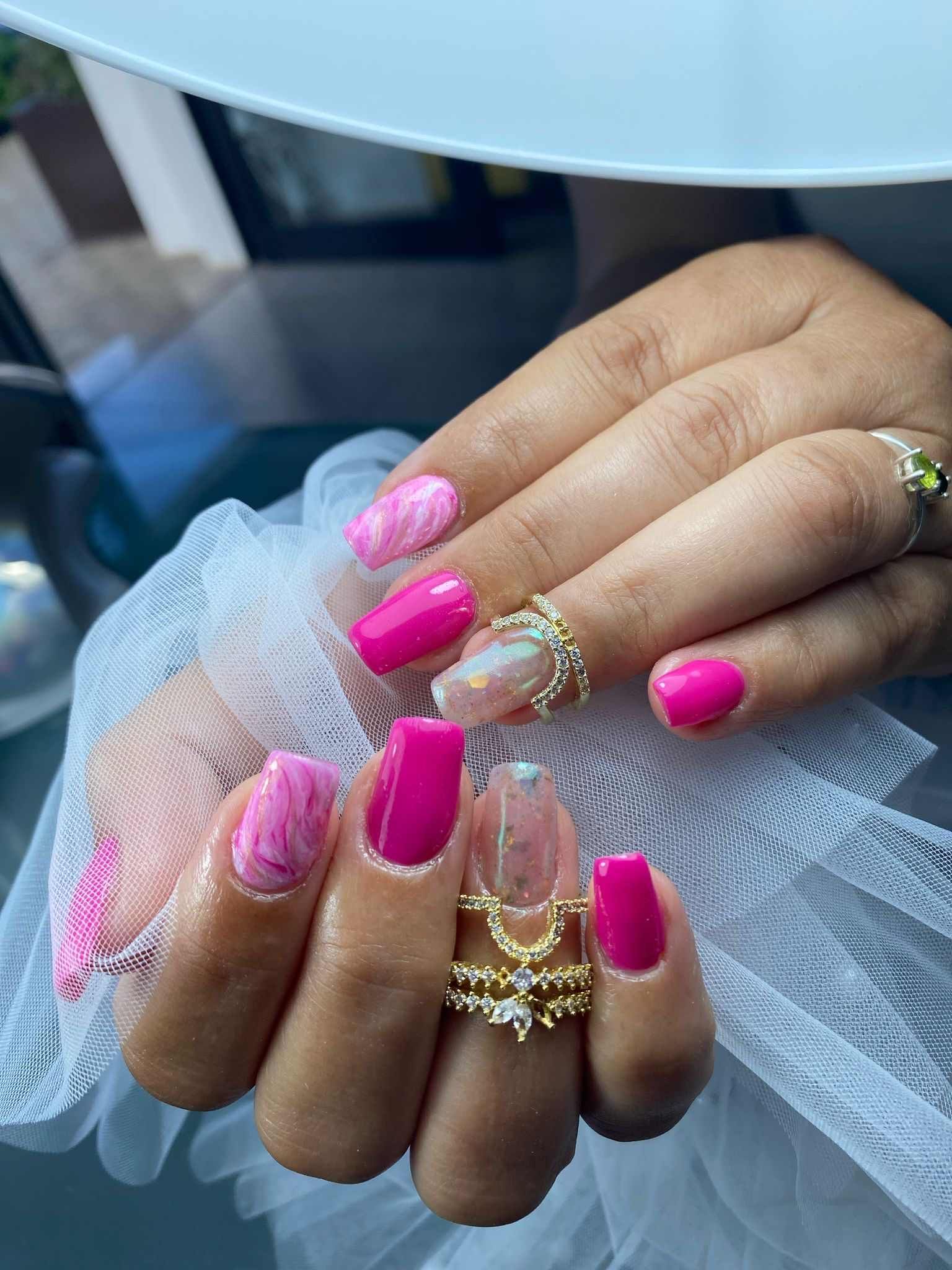 Un primer plano de las manos de una mujer con uñas rosas y anillos.