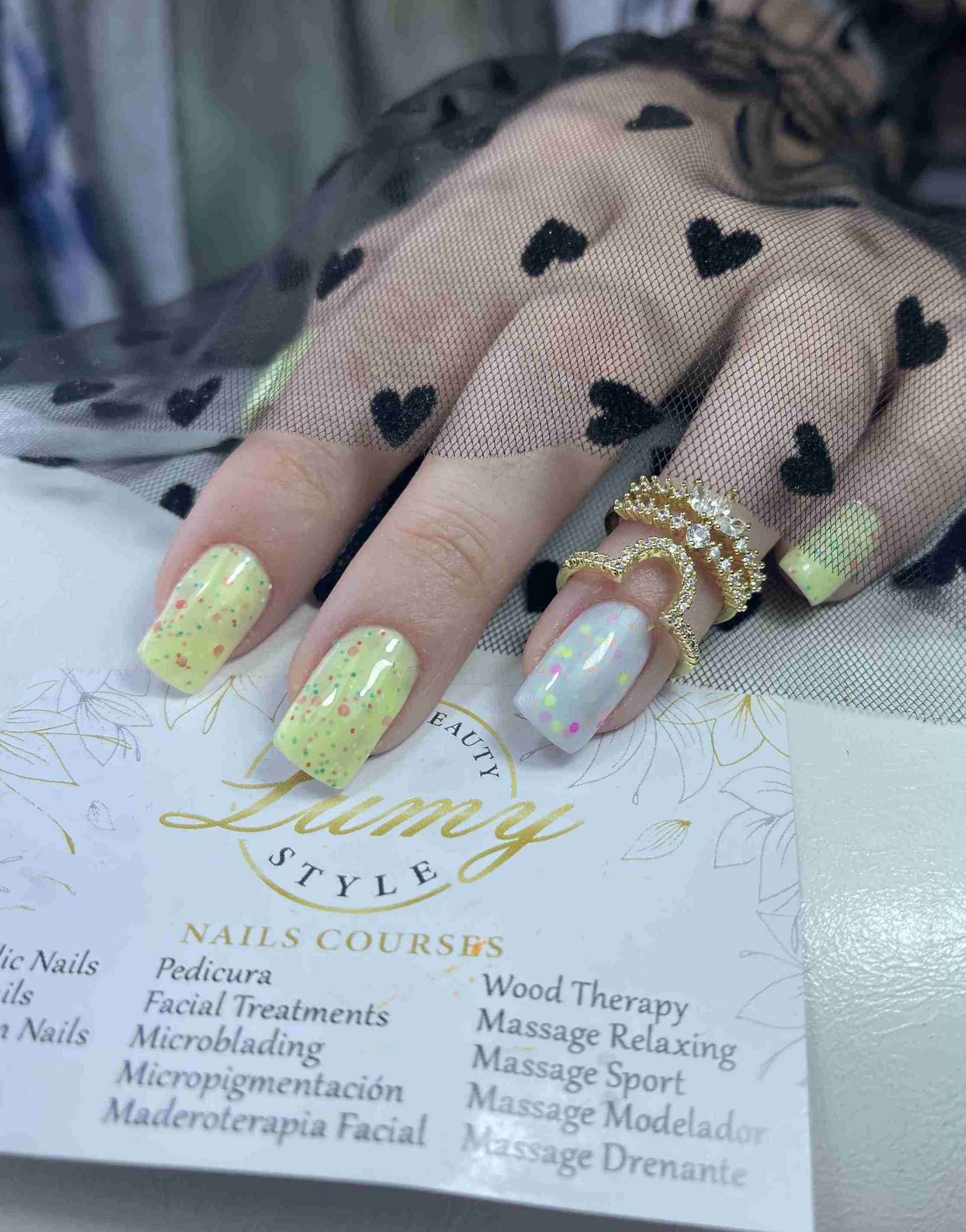 Un primer plano de la mano de una mujer con uñas amarillas y anillos.