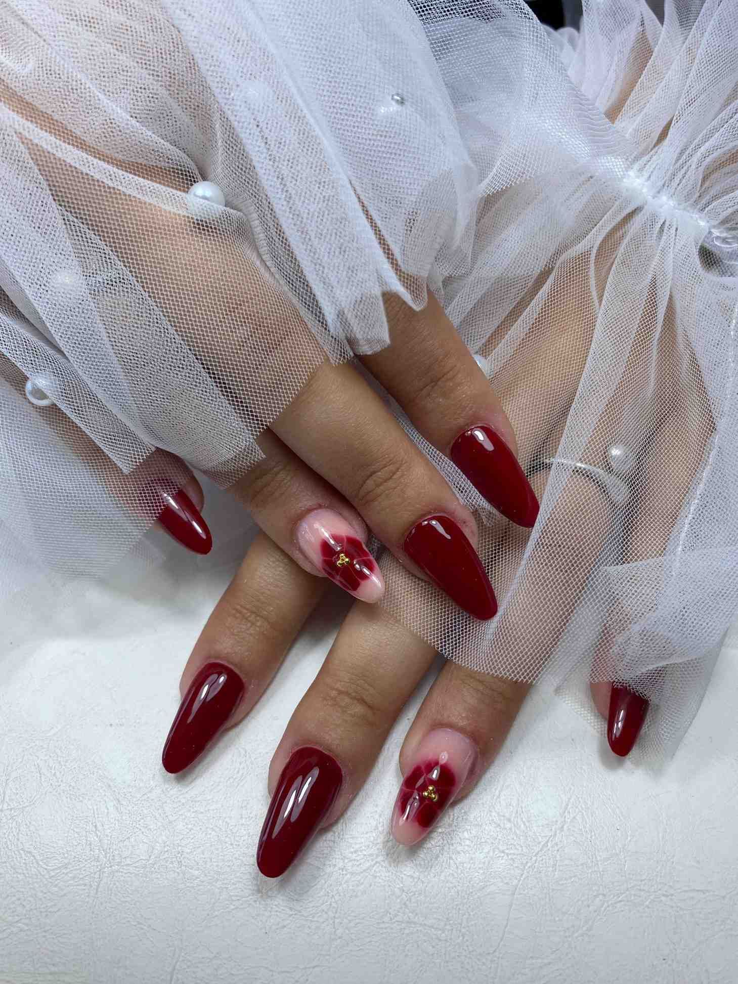 Un primer plano de las manos de una mujer con uñas rojas y un guante de encaje blanco.