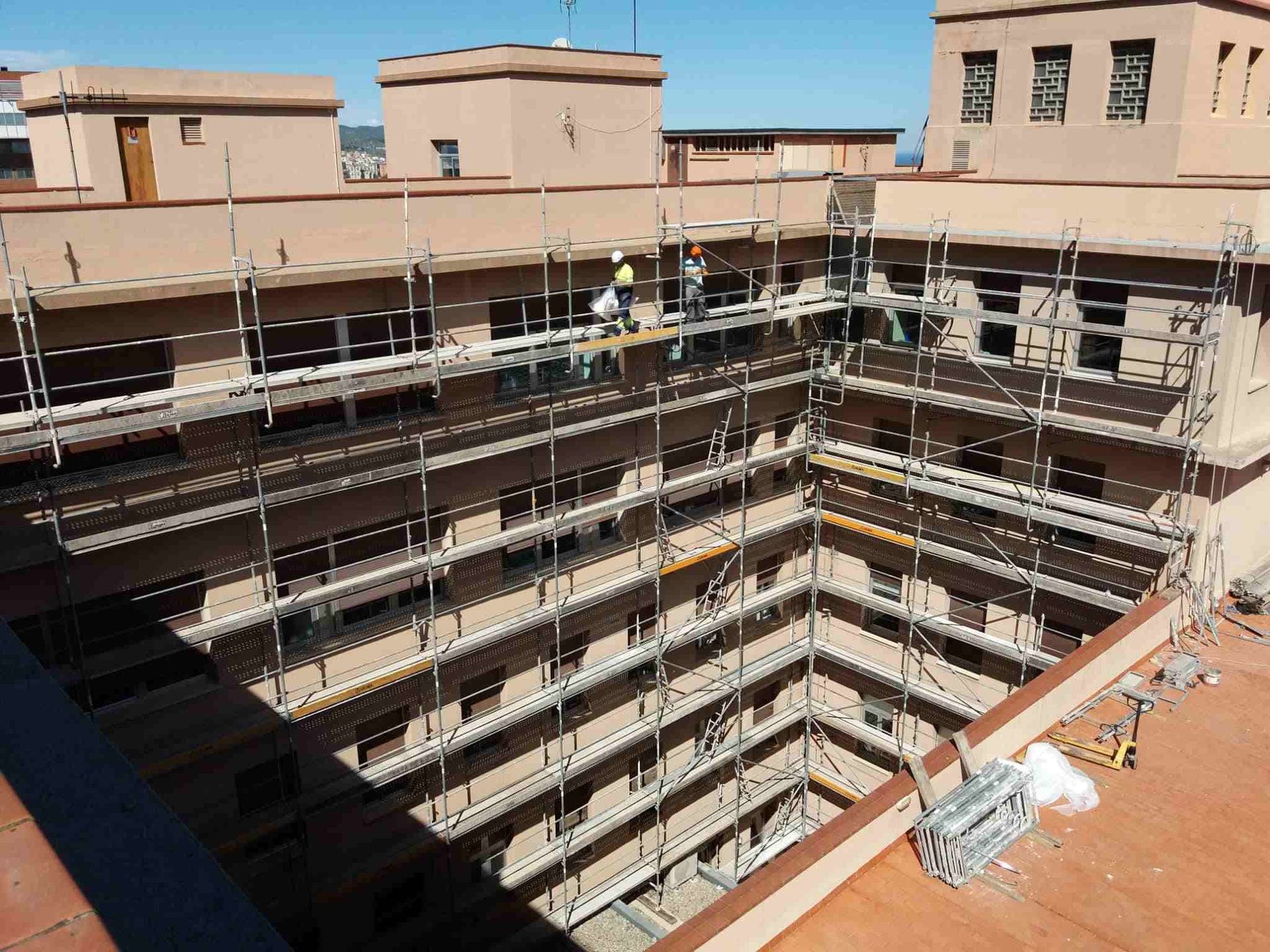 Exterior de edificio en construcción con andamios y trabajadores.