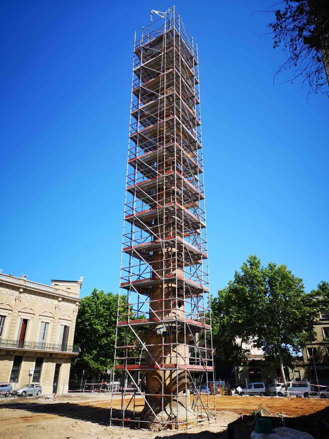 Un alto monumento en restauración, rodeado de andamios. Con el cielo azul despejado como fondo.