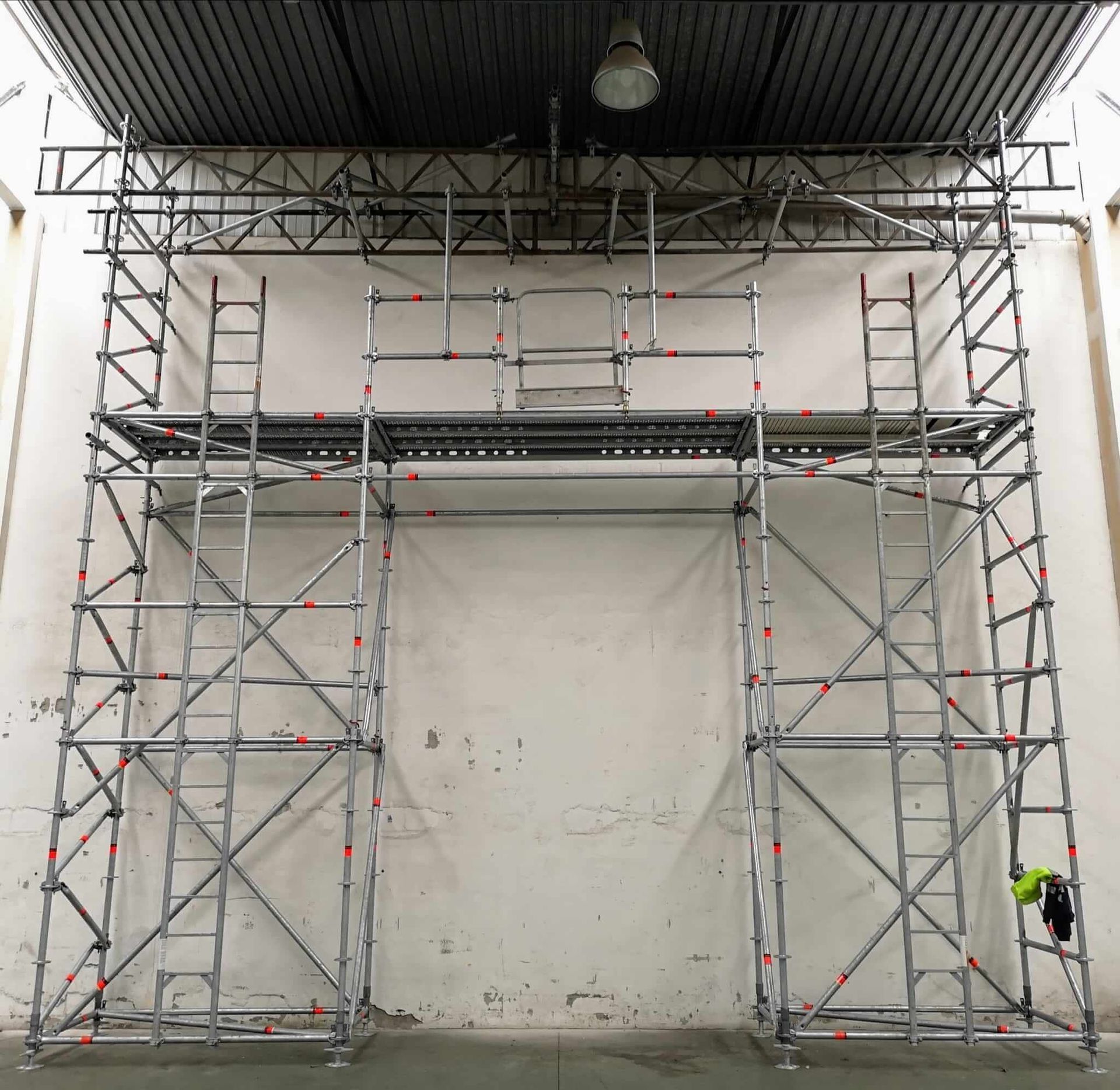 Estructura de andamio contra una pared blanca en un entorno oscuro.