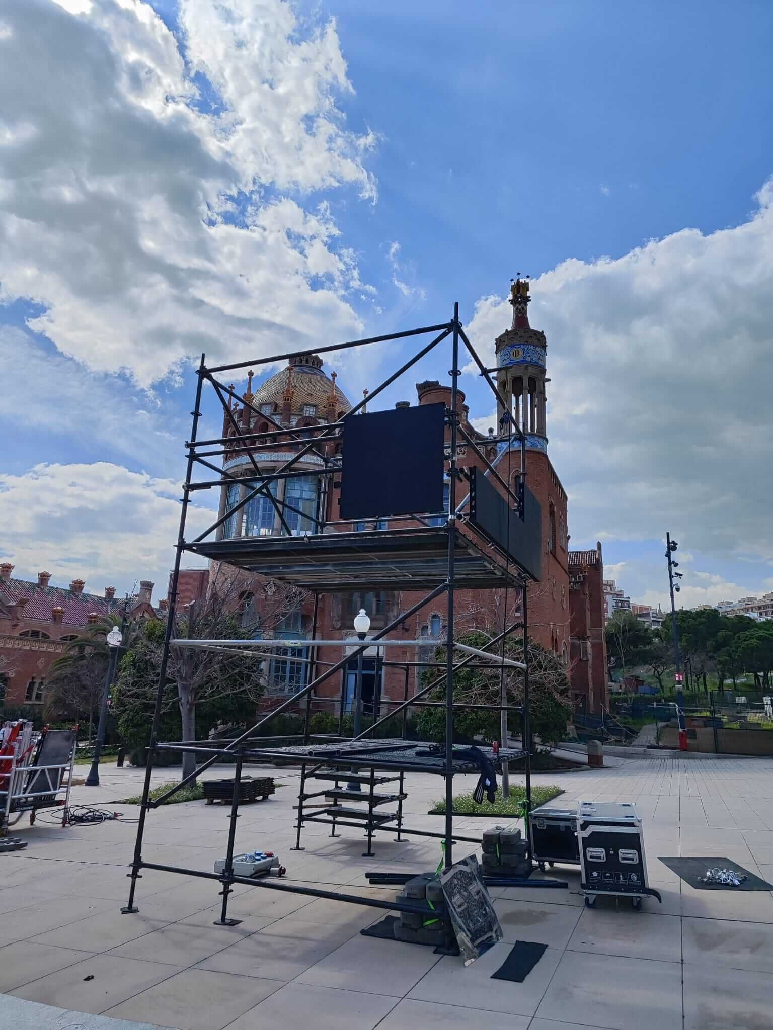 Andamios delante de un edificio de ladrillo con cúpula y torre en un día soleado.