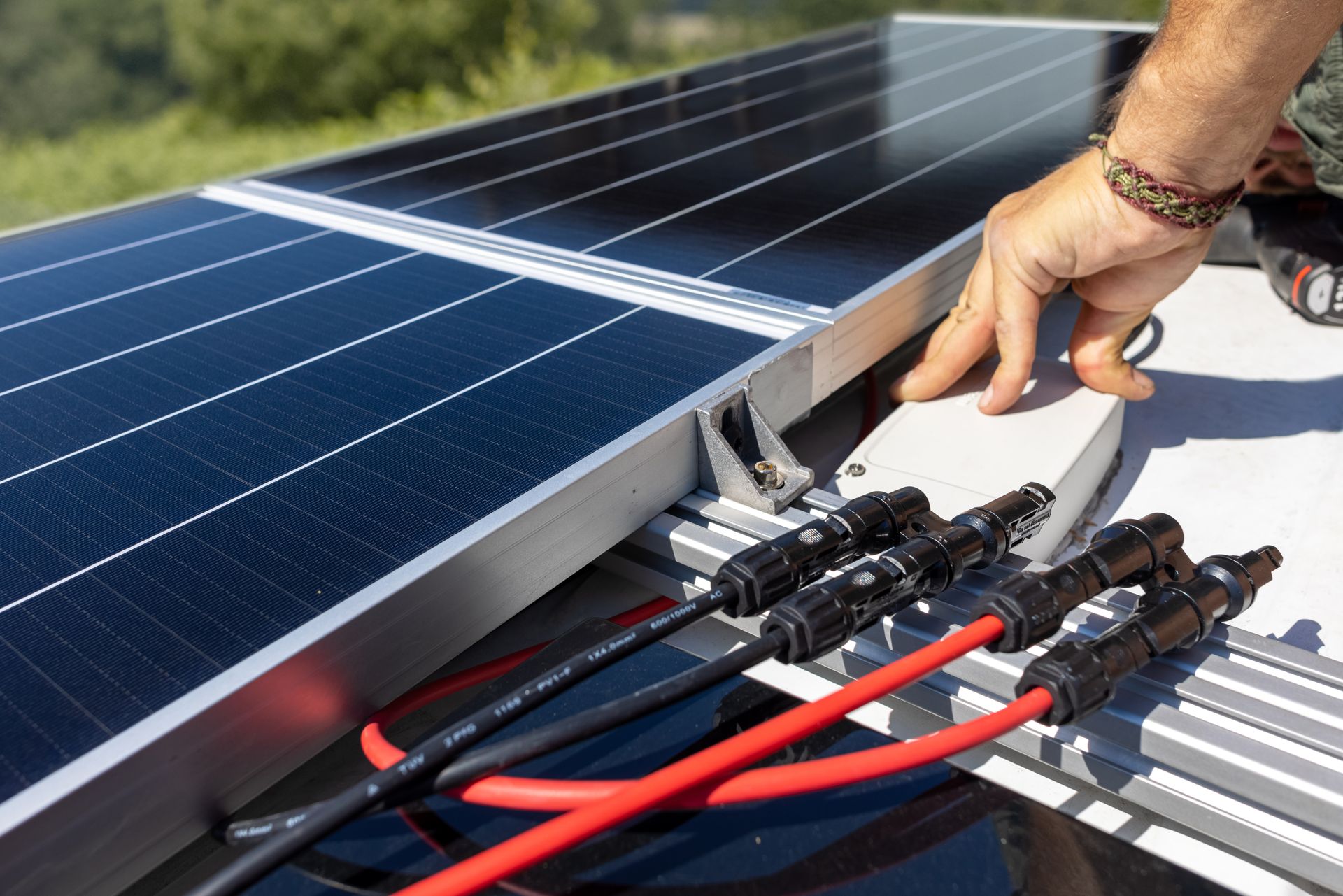 Raccordement manuel des fils des panneaux solaires à des connecteurs noirs sur un ensemble de panneaux.