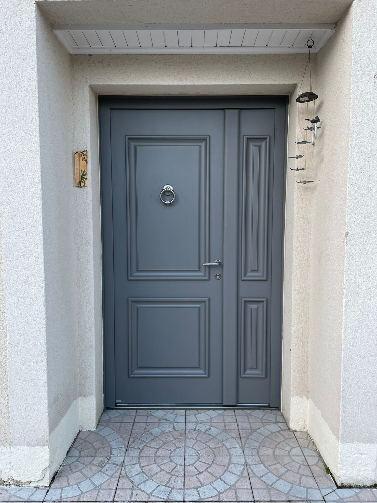 Porte d'entrée grise à deux vantaux.