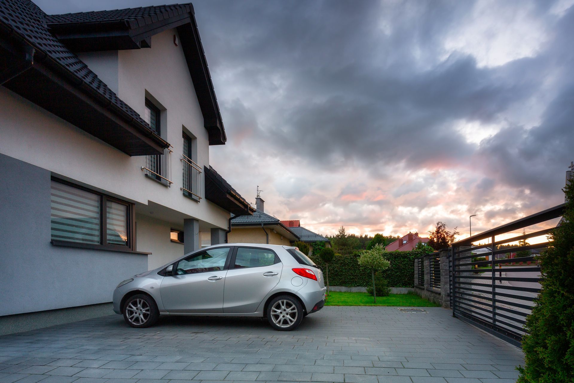 Une voiture garée dans la cour d'une maison avec le portail fermé. 