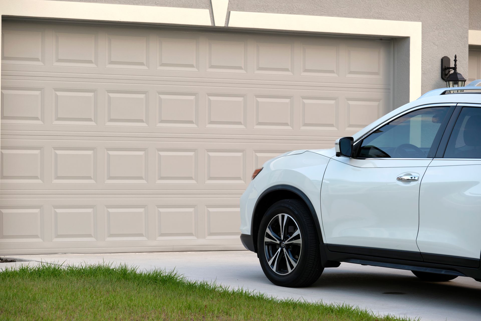 Une voiture en face d'une porte de garage blanche.