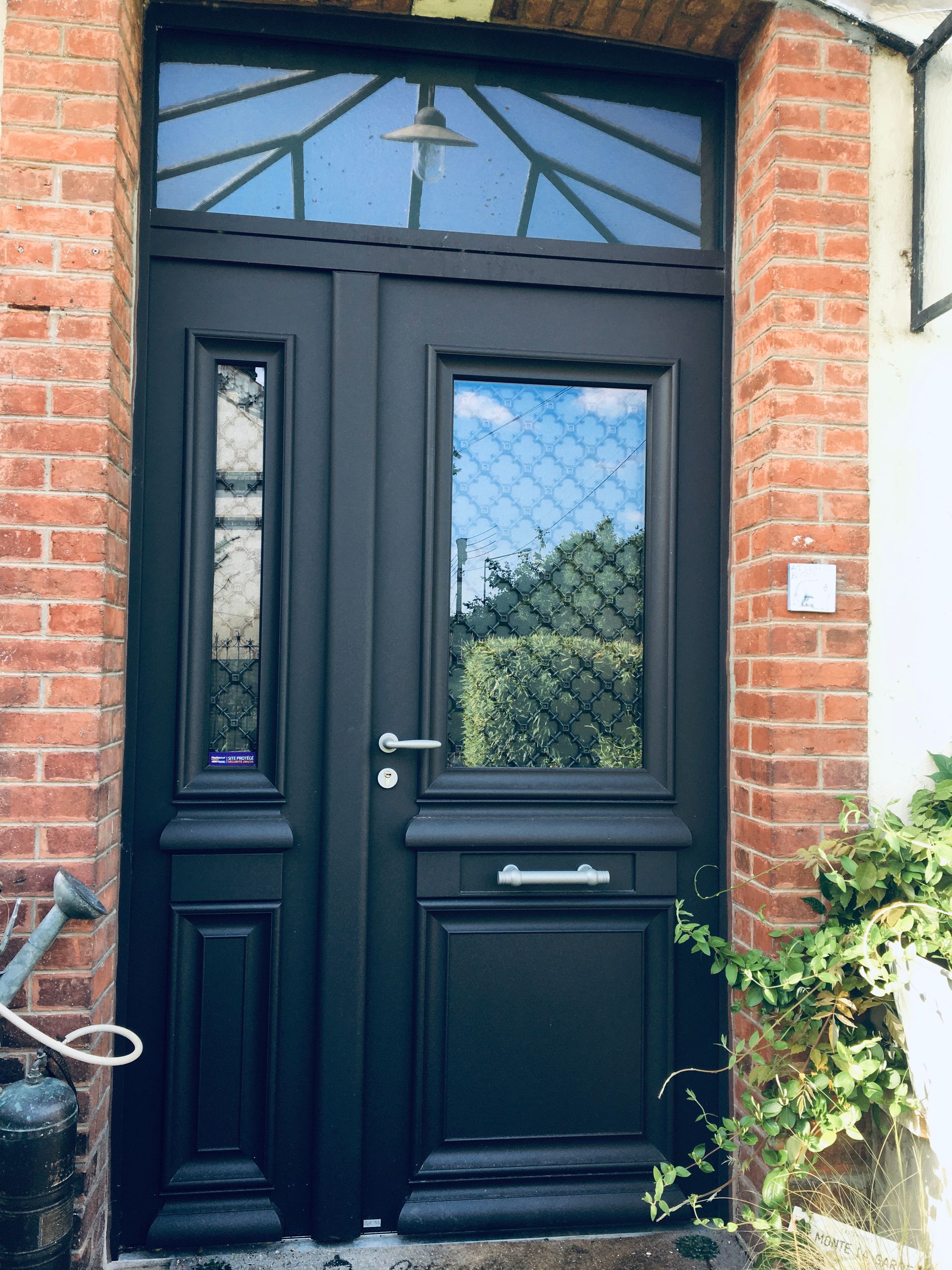 Porte d'entrée grise avec le vitrage design.