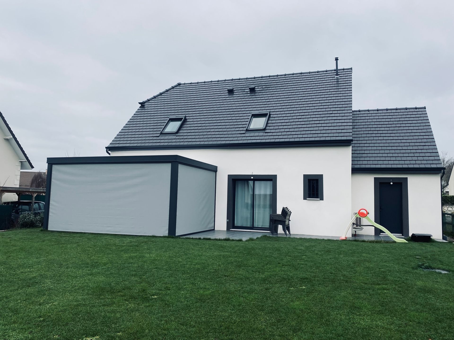 Une pergola équipée des stores attenante à une maison.