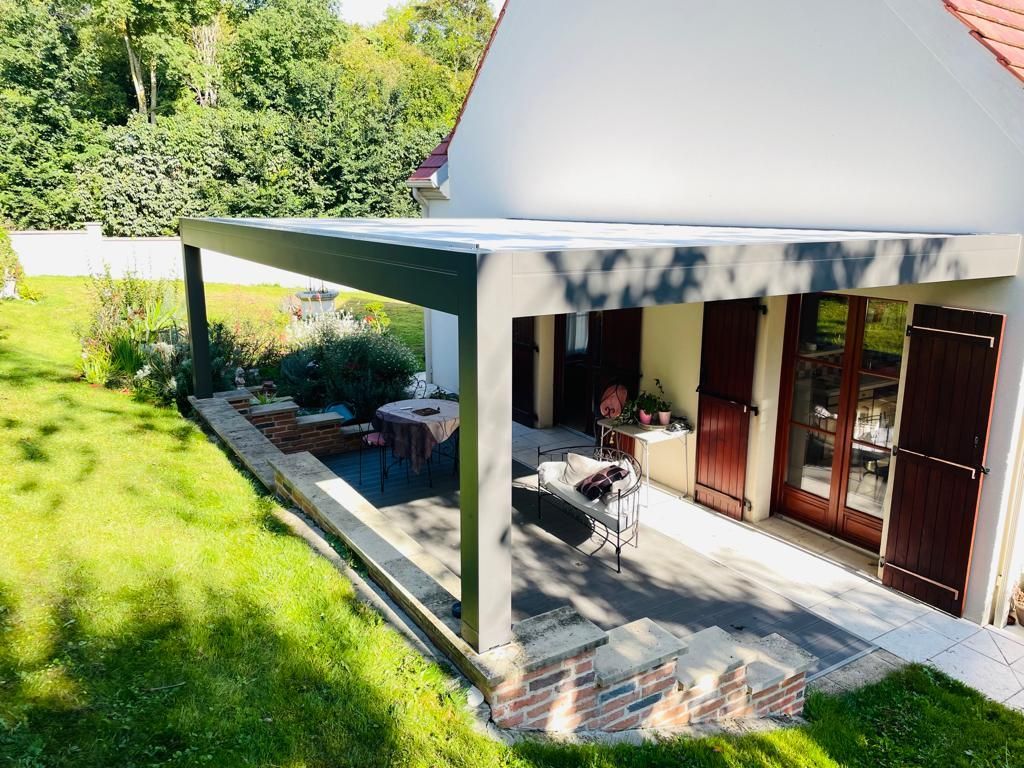 Une pergola avec la structure en aluminium adossée à la maison.