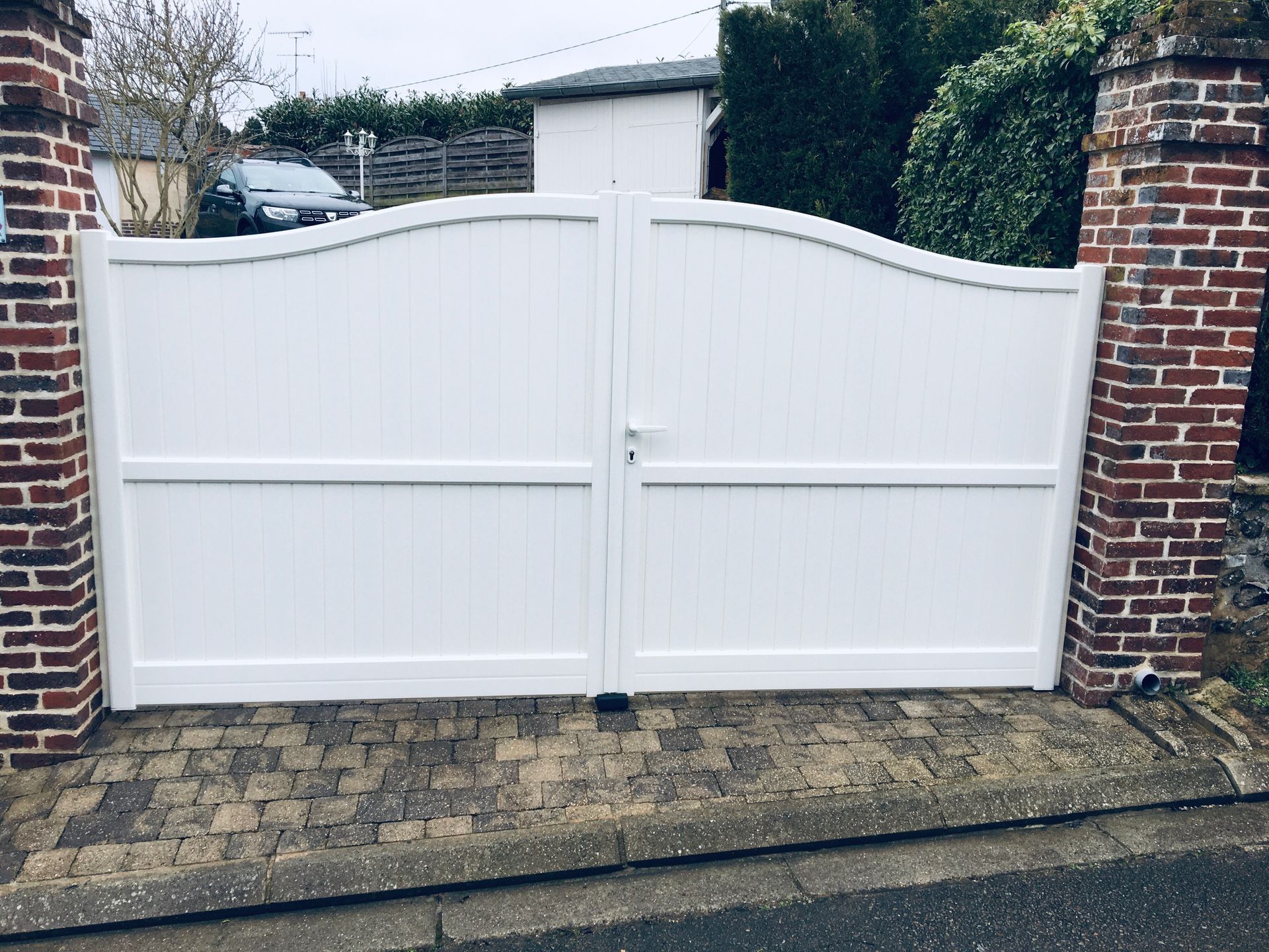 Portail battant blanc arqué.