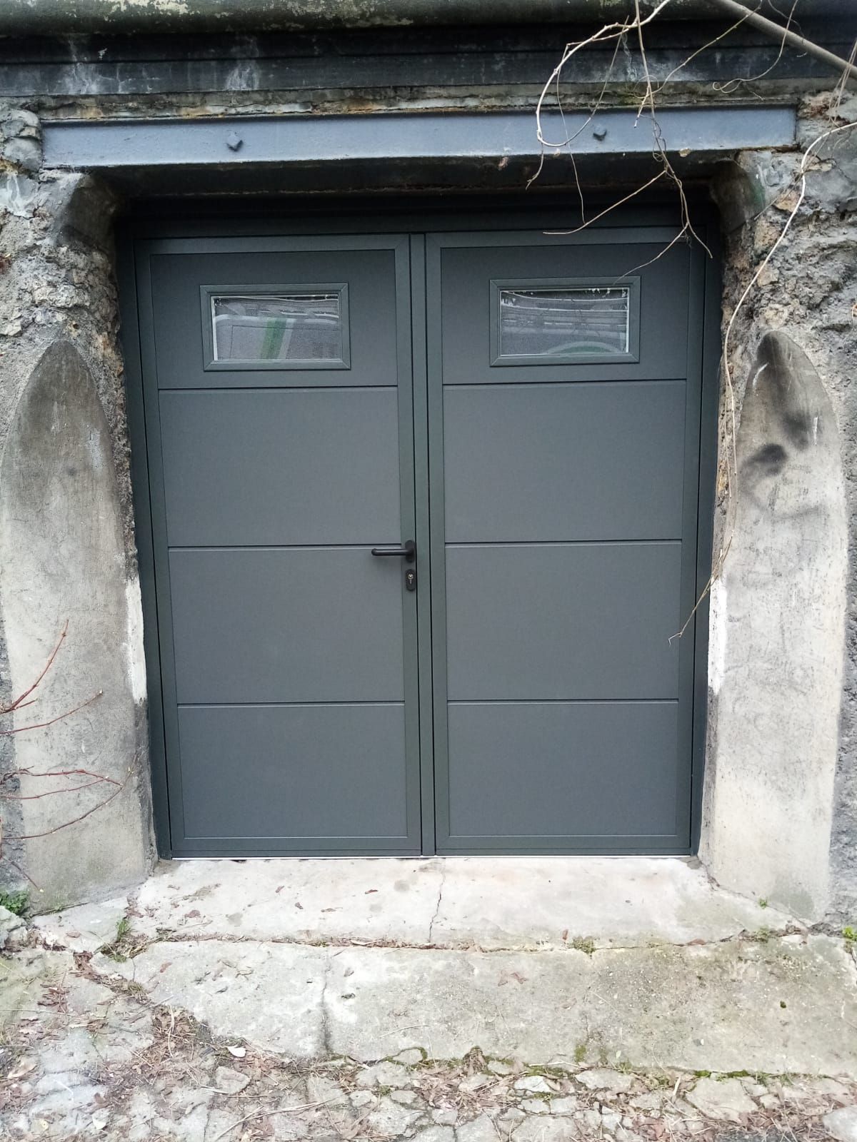 Porte de garage battante grise.