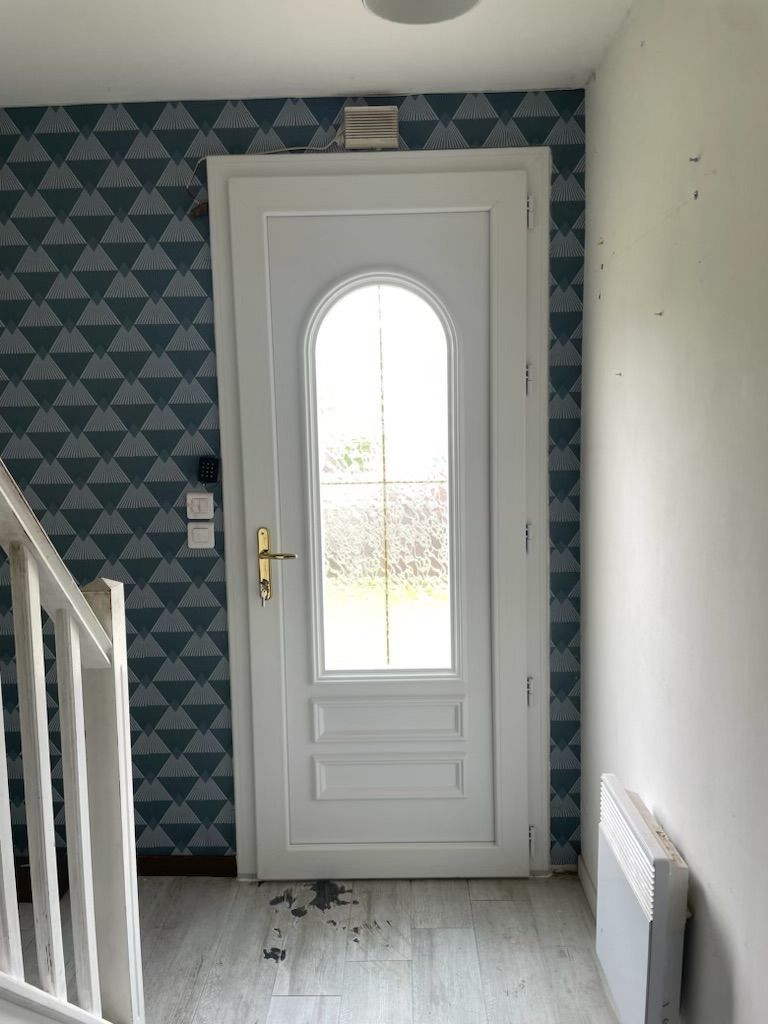 Une porte blanche avec le vitrage arrondi, vue de l'intérieur.