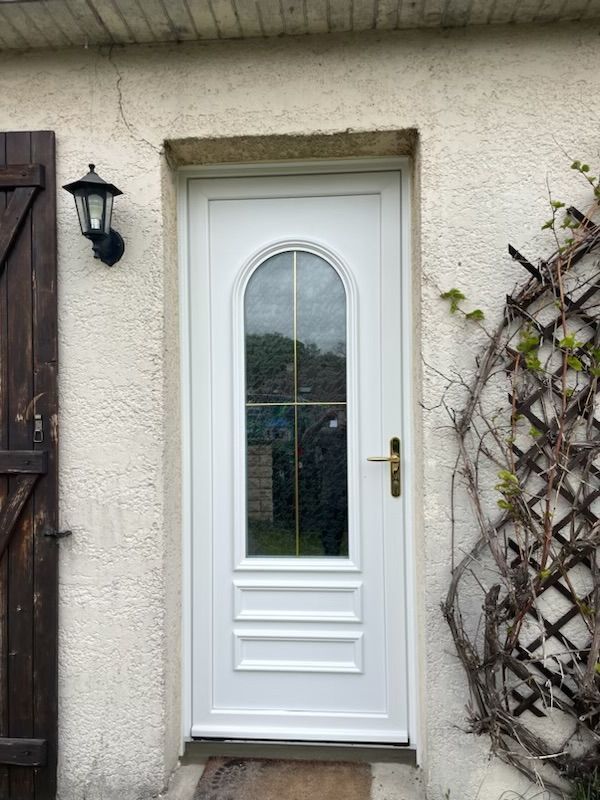 Une porte blanche avec le vitrage arrondi.