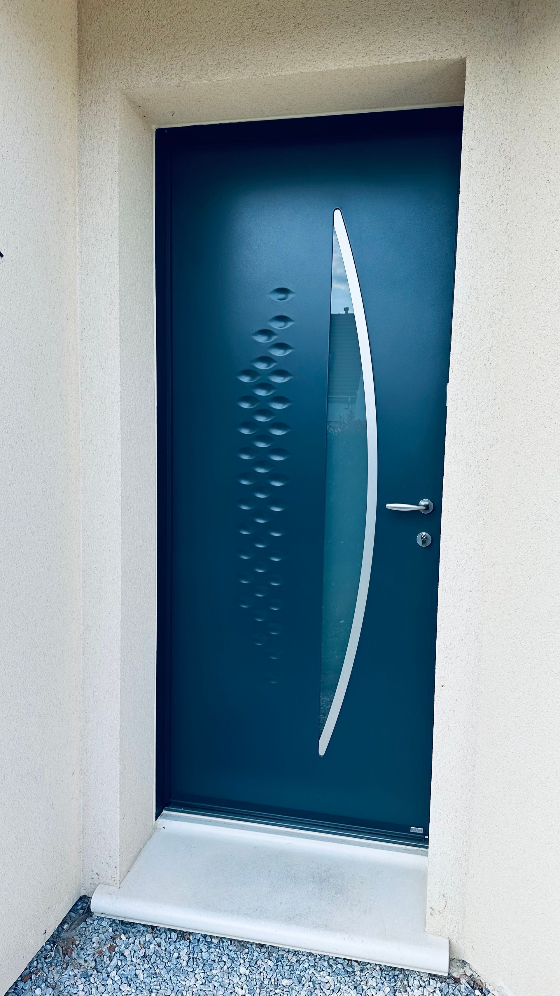 Une porte d'entrée bleue avec le vitrage arrondi.