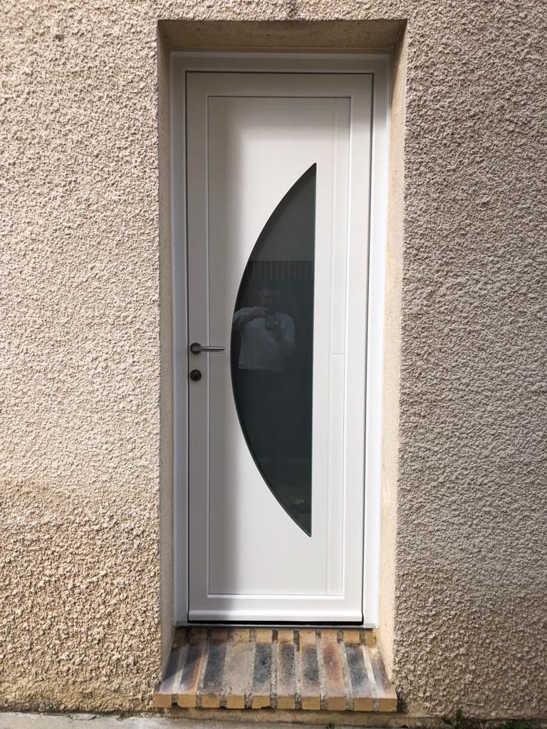 Une porte d'entrée blanche avec le vitrage arrondi.